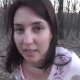 A brunette woman takes a nice-sized dump in a wooded location outdoors.